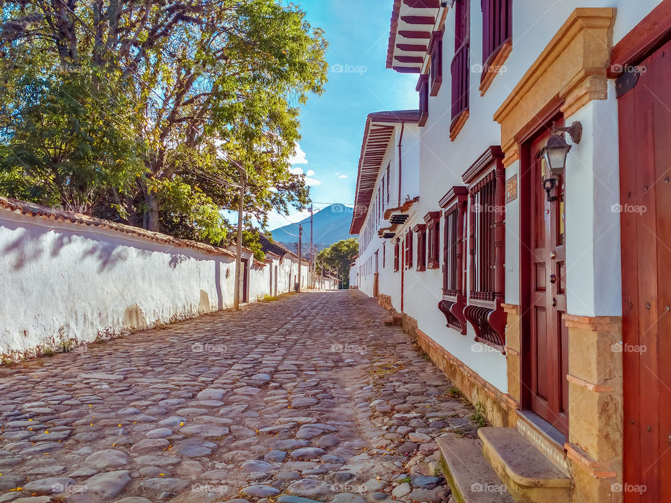 Calle de Villa de Leyva, Boyacá, Colombia en una mañana soleada y con cielo azul. Fachadas de casas, arquitectura colonial. Villa de Leyva street, Boyacá, Colombia on a sunny morning with blue sky. Facades of houses, colonial architecture.