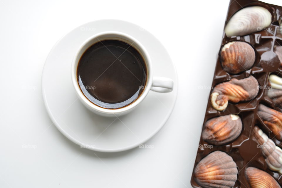 cup of coffee and chocolate candies on a white background top view, morning routine