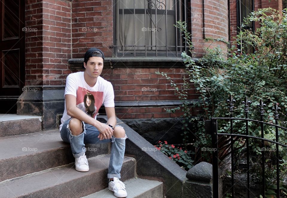 Young man sitting on steps outside house