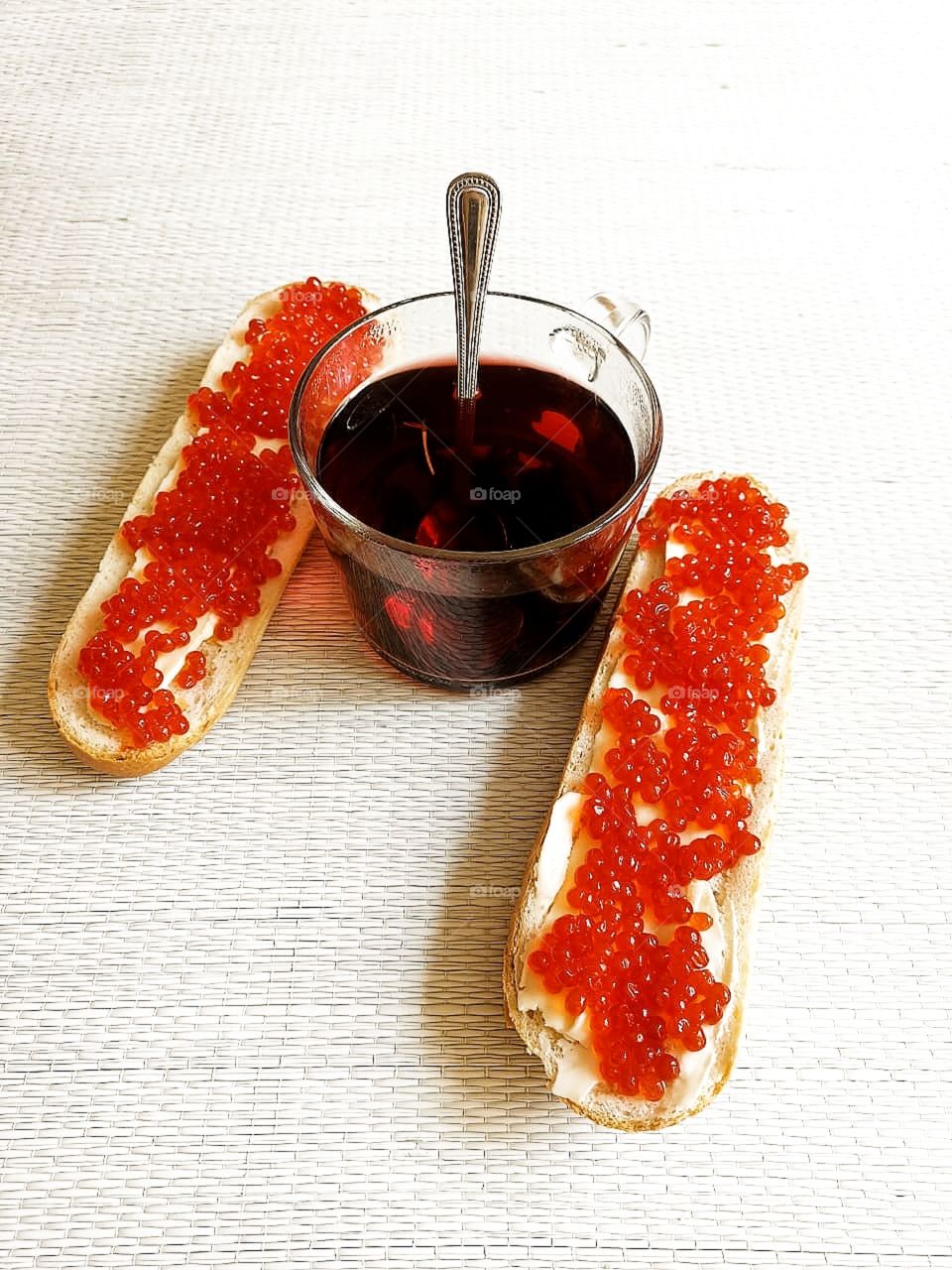 Breakfast. A cup of tea and two rolls with butter and red caviar