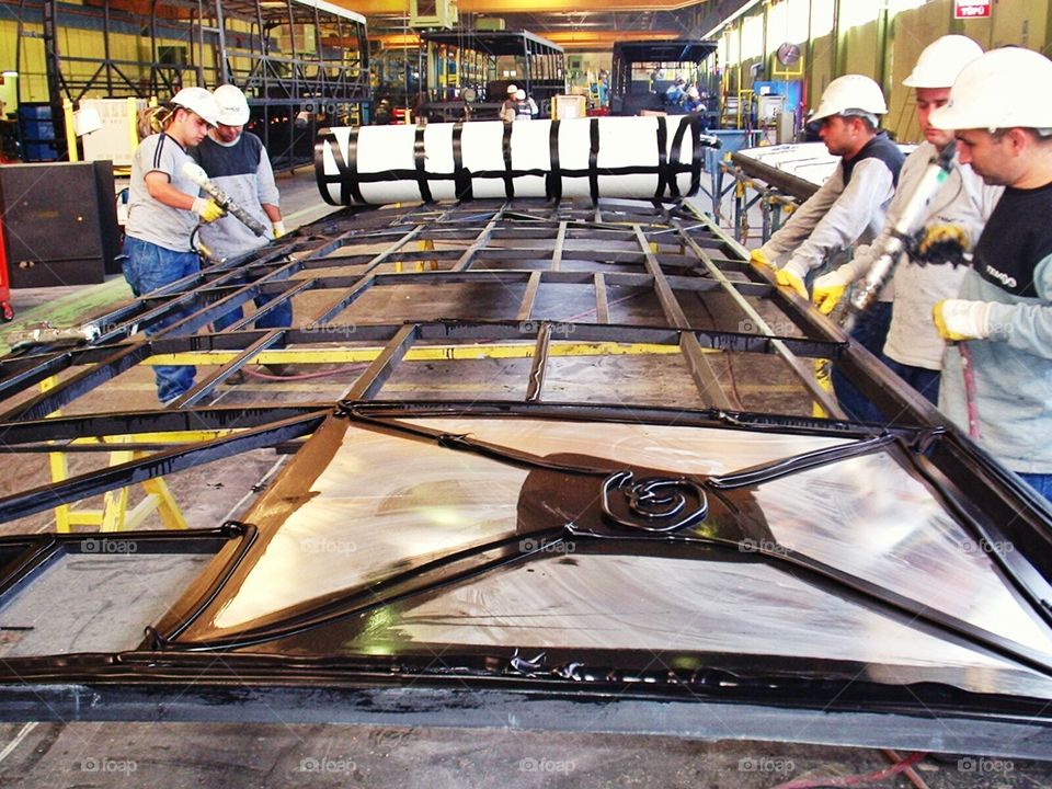 workers on work. Workers are working on the roof part of a bus.