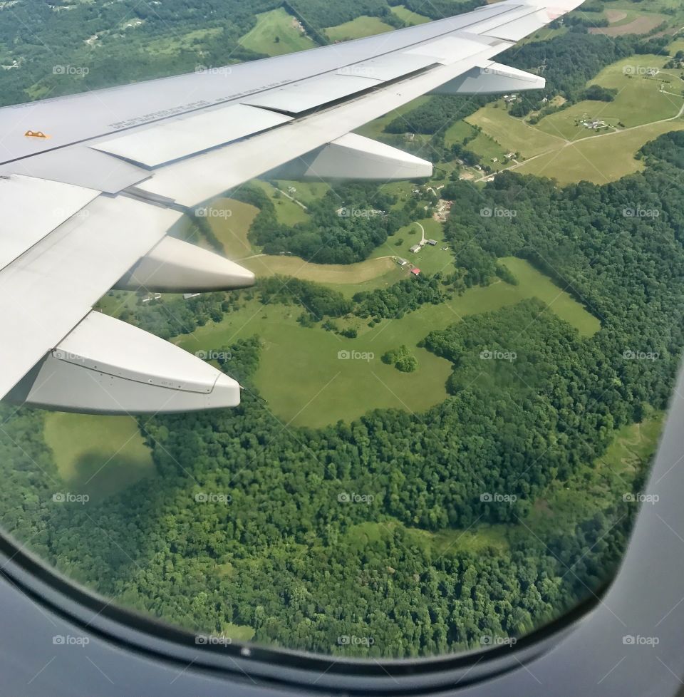 View from airplane window revealing the plane wing and the landscape below