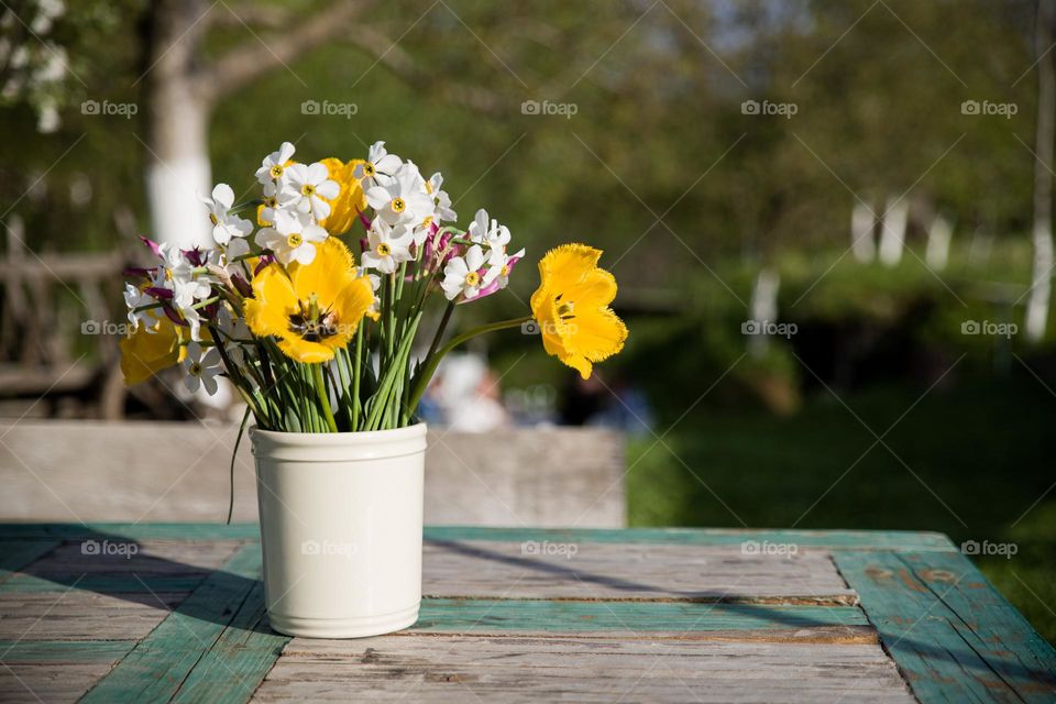 Spring flowers in a vade at a restaurant that has a courtyard in a beautiful garden with a small river crossing the courtyard.