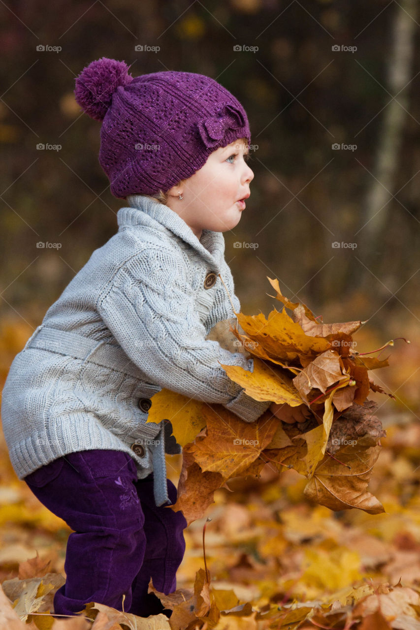 Girl playing with autumn leafs
