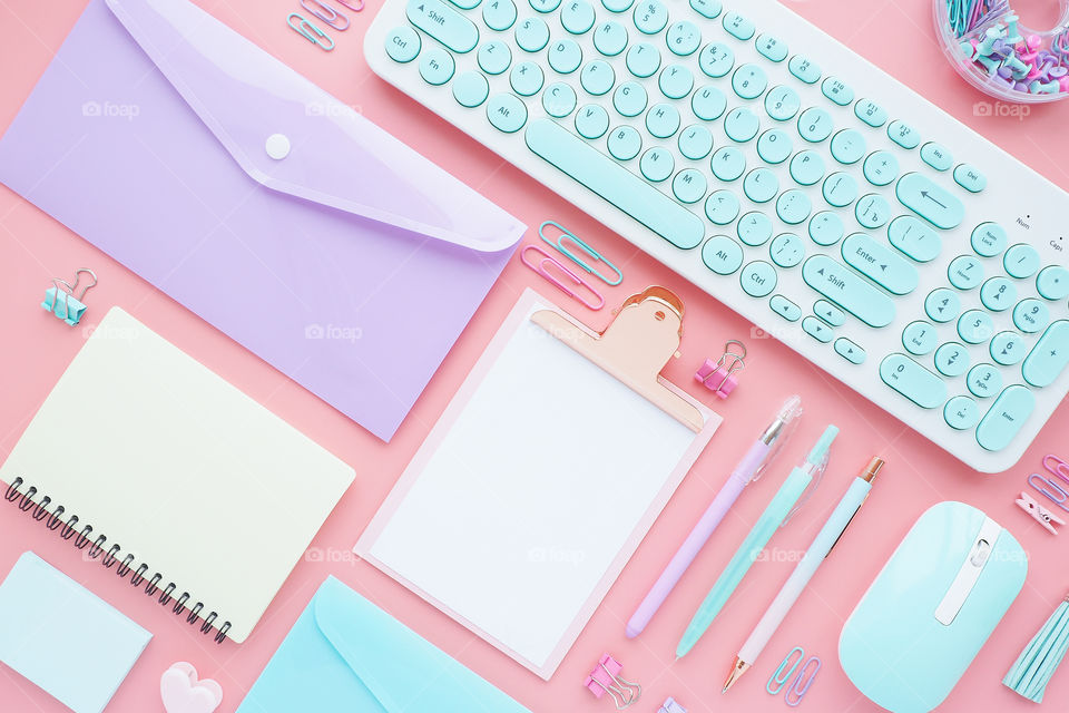stationery, office supplies and keyboard on a pink background.
