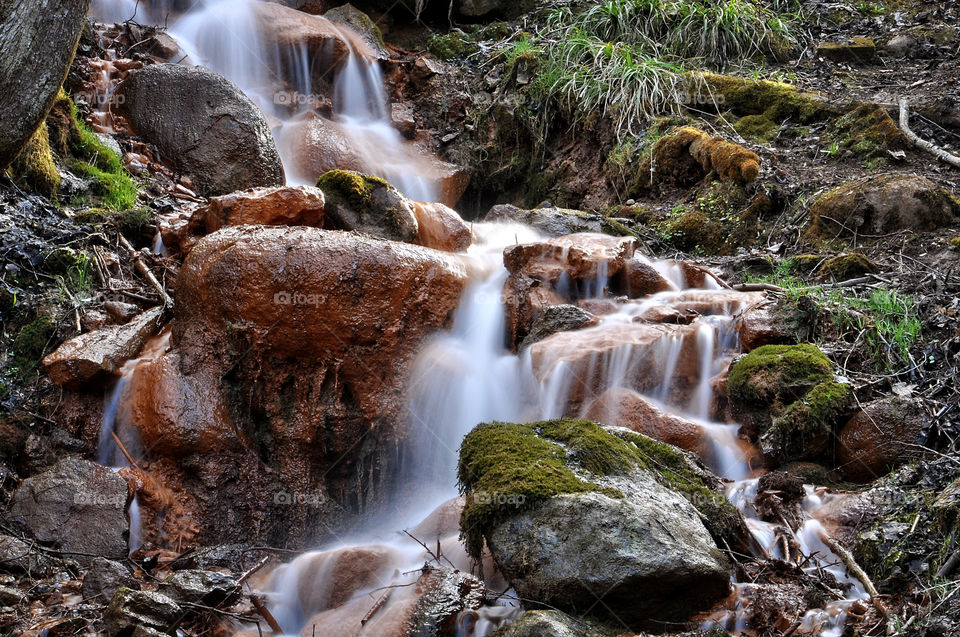 Sources with ferrous impurities flowing over large stones.