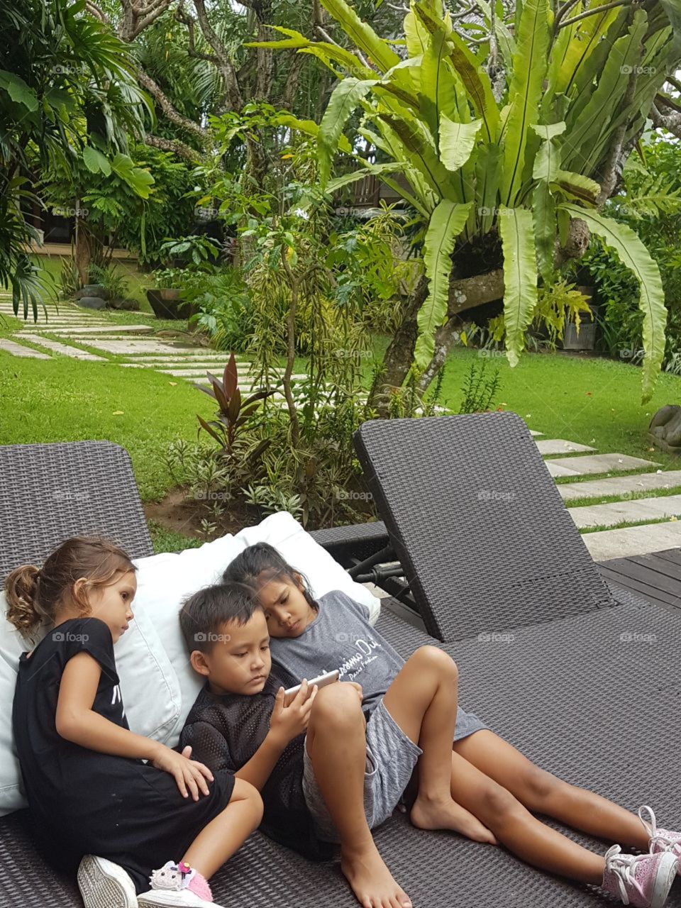 This is beautiful yet sad at the same time. This, represents how technology has changed the world. Three kids out in the big beautiful garden, during summer, yet completely unaware of their beautiful surroundings.