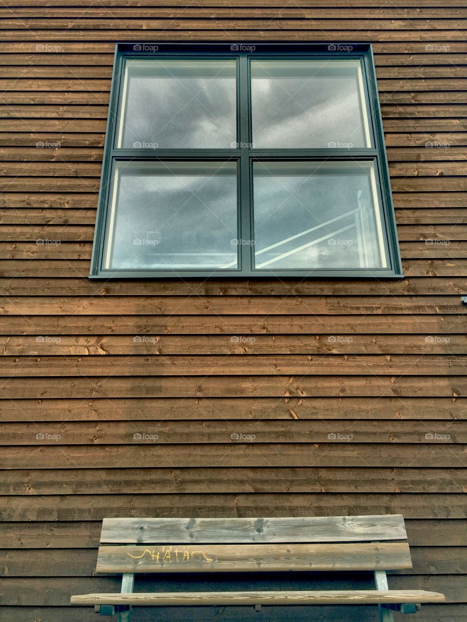 Reflecting the sky. Square window in wooden wall with sky reflection