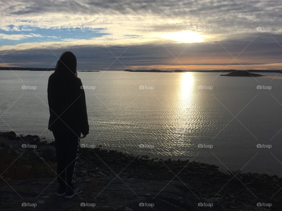 Girl watching the calm sea in the sunset