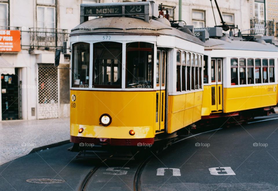 Lisbon street with old historical buildings and yellow trams. Traditional yellow tramp in Lisbon, Portugal, no people.