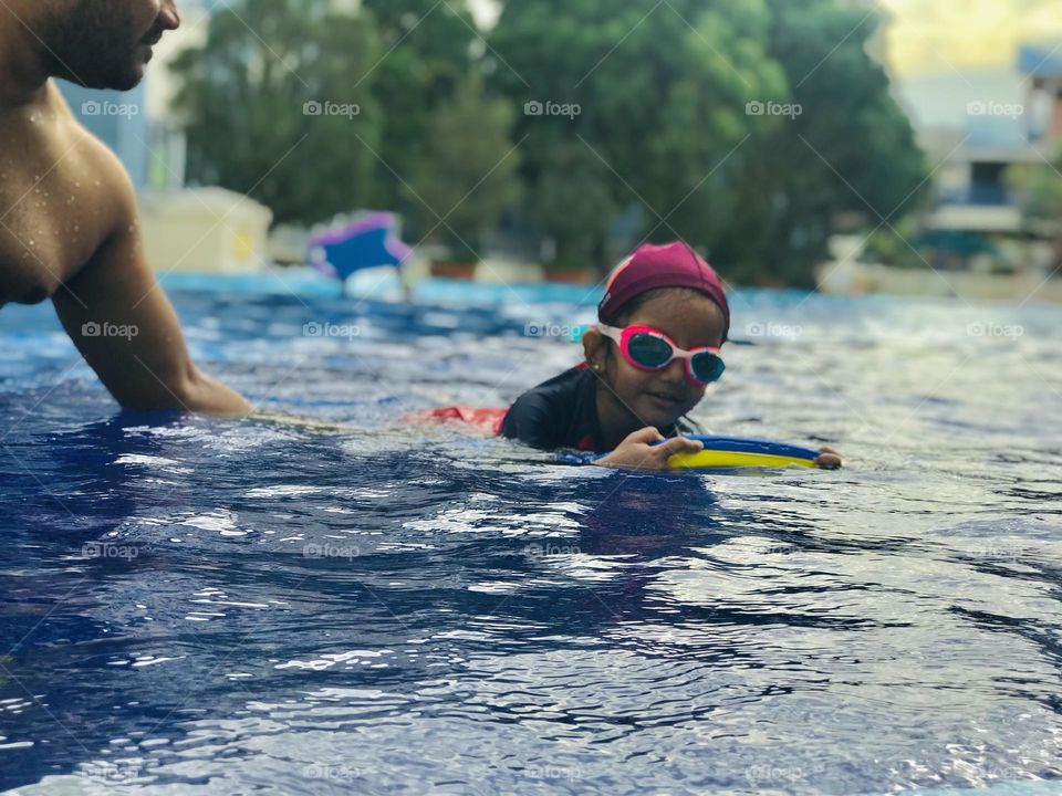 A girl swims at swimming pool.