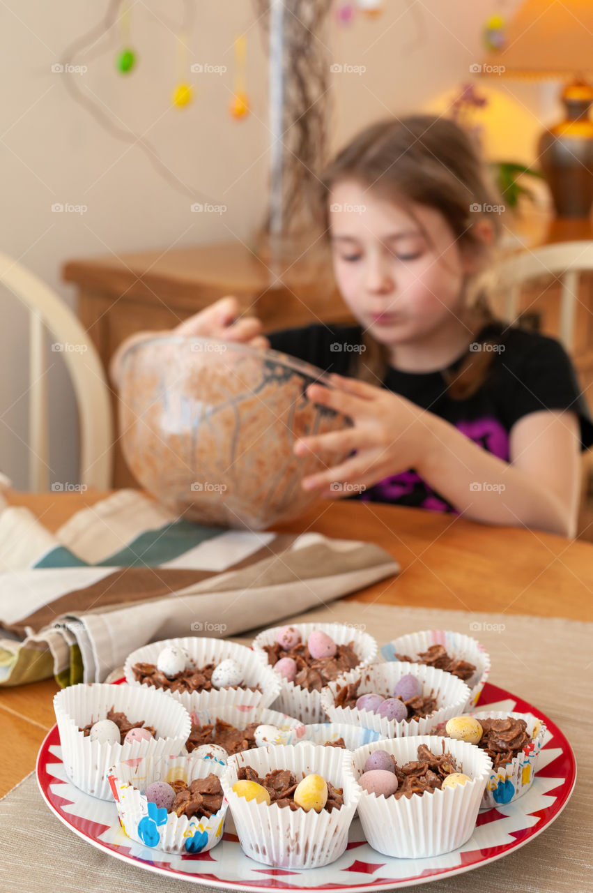 Young girl just finished making chocolate oats cupcakes decorated with small candies.