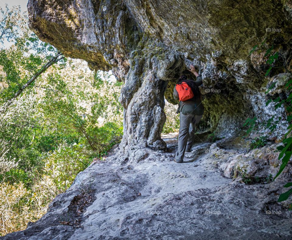 A hiker passes through a natural archway in a rocky outcrop 