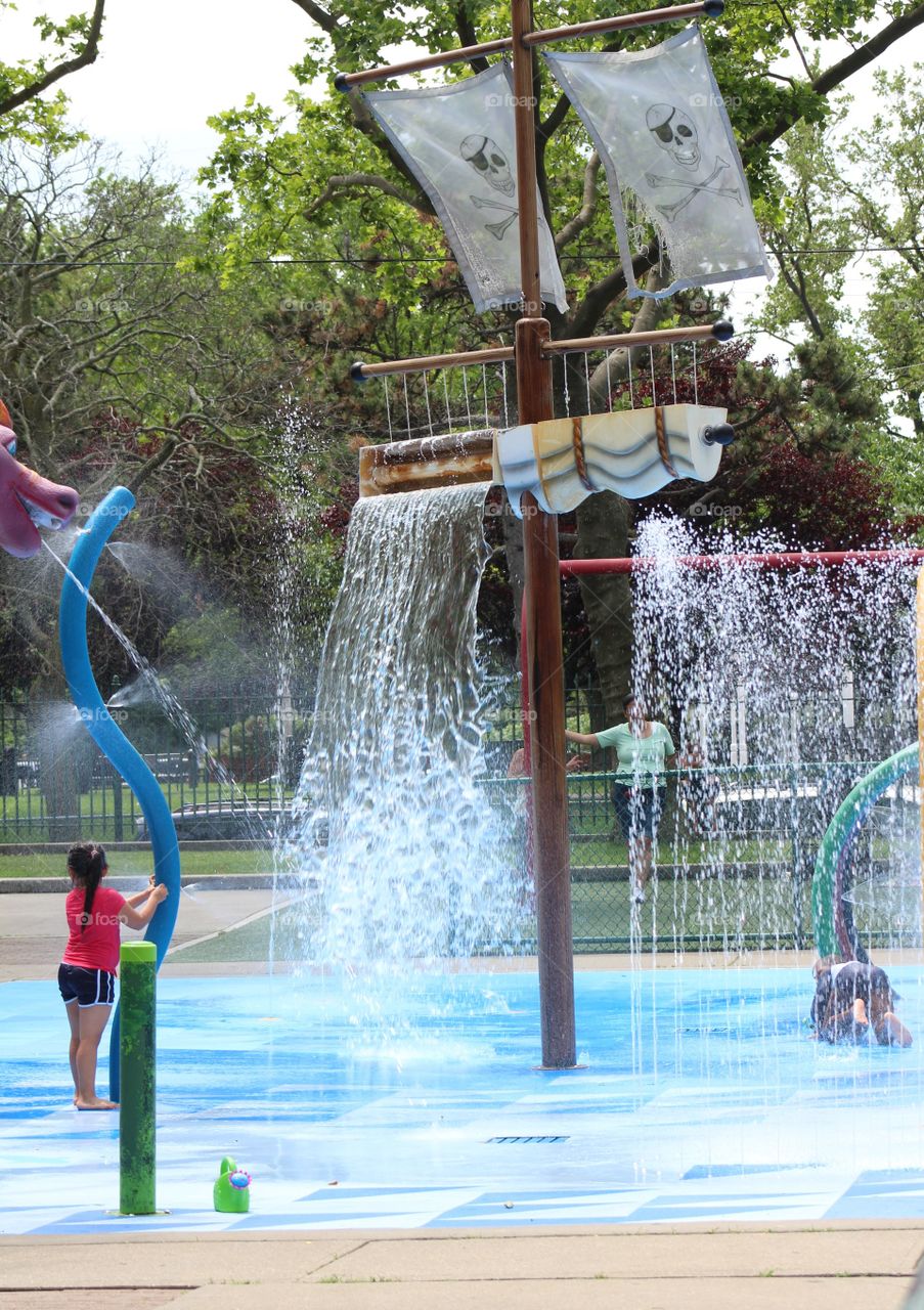 Little girl playing in waterpark with pirate-themed sprays in June 