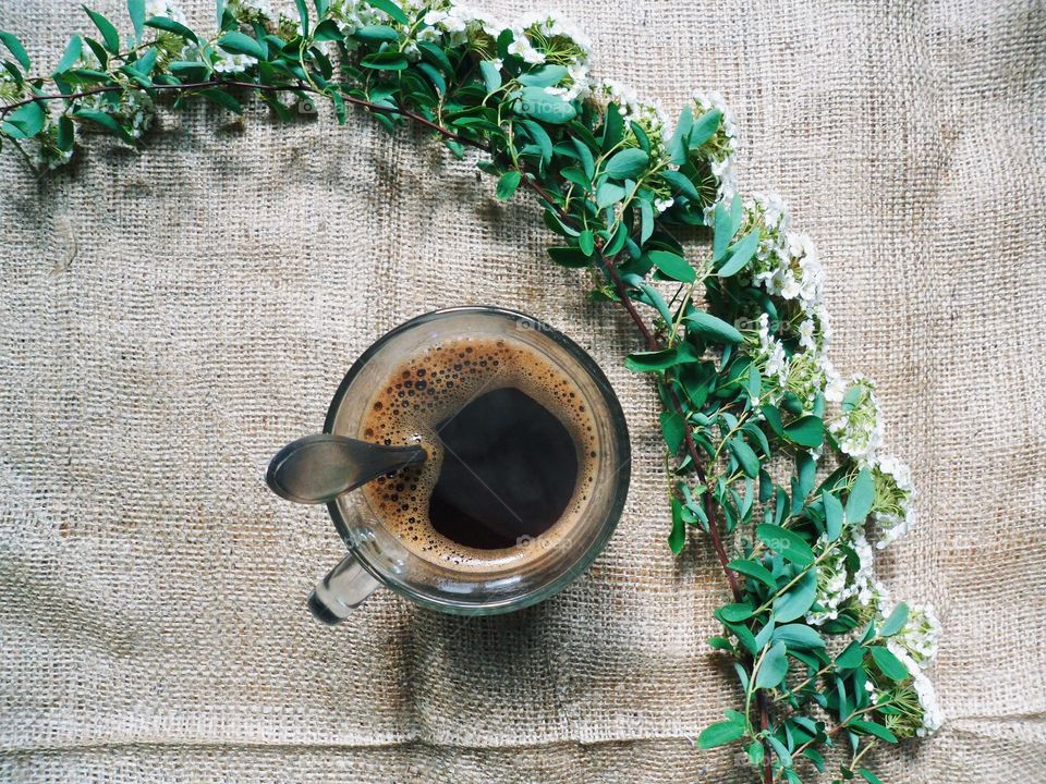 a cup of black coffee and a branch with flowers