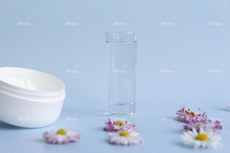 Jars with cosmetic products, beauty cosmetics in a white jar with cream and water with fragrant flowers.