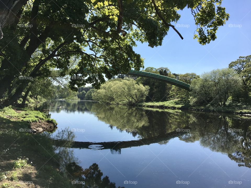 Picturesque view of the riverbank spoilt by a blot on the landscape water pipe but it looks pretty as a reflection and you can just make out circular waves made by a fish