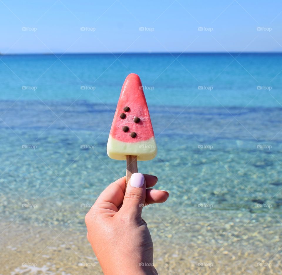 Woman holding watermelon ice cream at beach