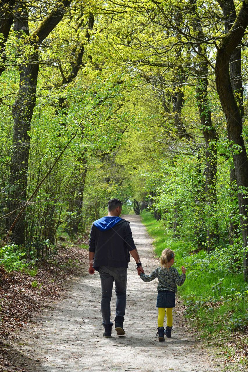 father and daughter walking on a footpath in the forrest