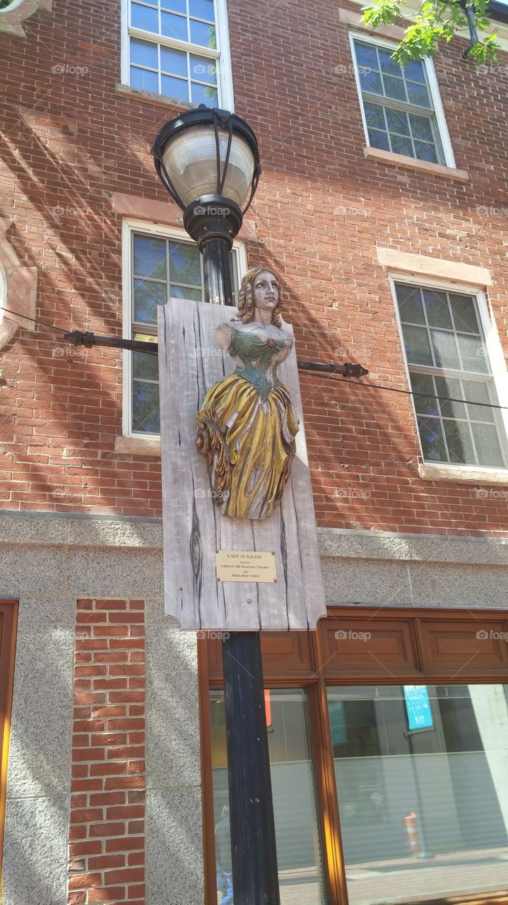 An outdoor plaque with a statue of a woman in Salem, MA.