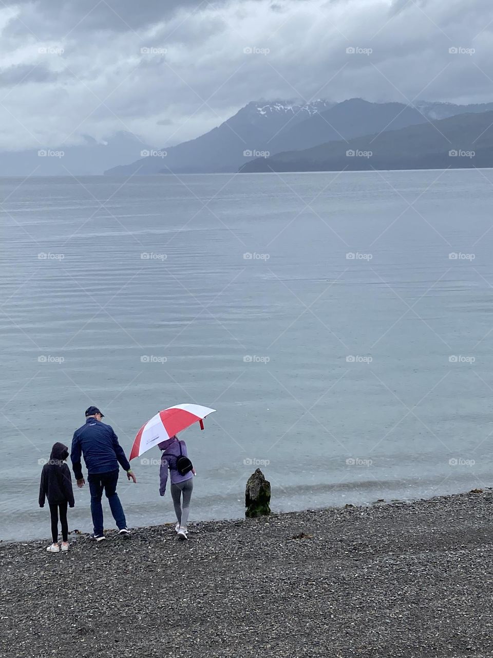 Family by the sea with a red umbrella.