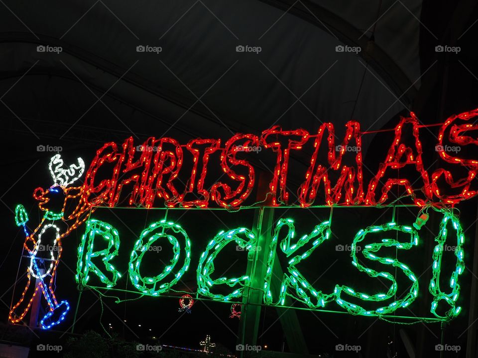 Christmas Rocks sign with a rockin’ reindeer display of Christmas Lights on a winter night. 