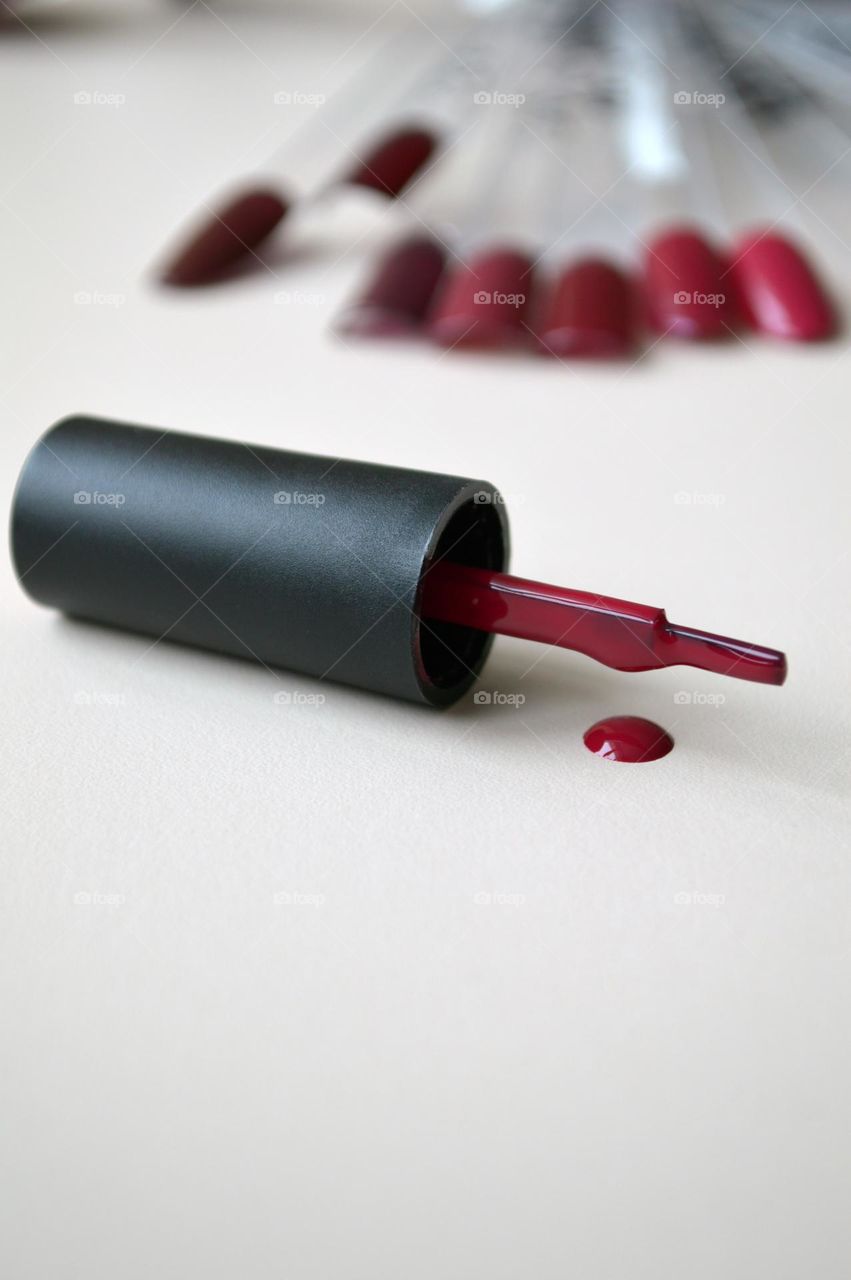 a drop of burgundy varnish of a magenta shade and a bone from the varnish on a beige background