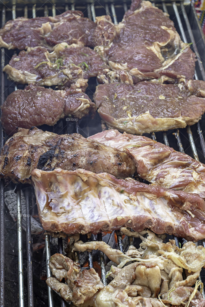 Pork and beef roast on the grill made of stainless tanks in park.