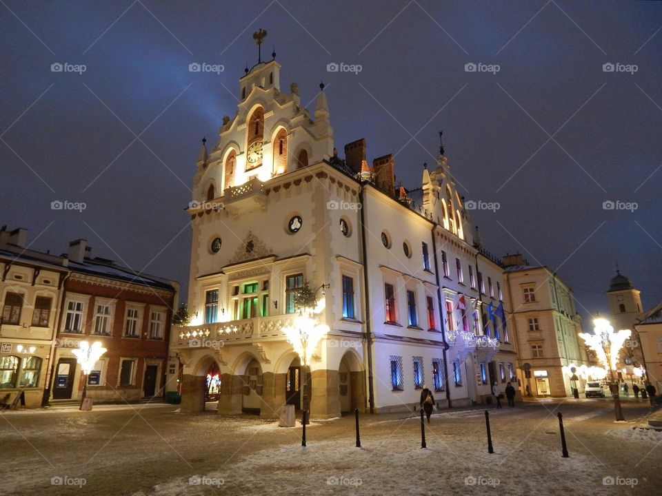 light in the windows of the building in the evening, square with lanterns, Poland