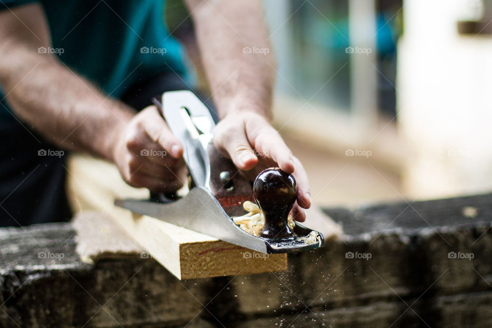 Image of my husband doing DIY at home,  preparing wood to make a table. Closeup image of wood, hand plane tool and wood dust and shavings.