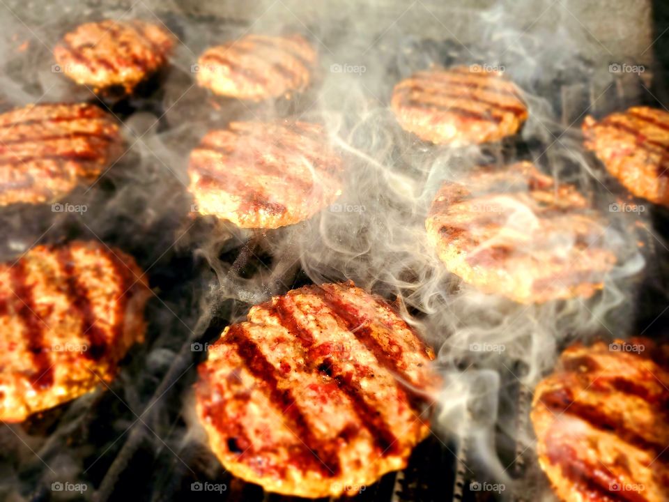 Hamburgers sizzle on a grill during a backyard celebration