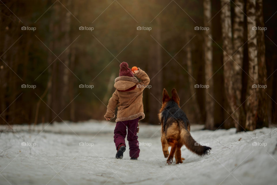 Little girl with German shepherd 6-th months puppy at early spring forest