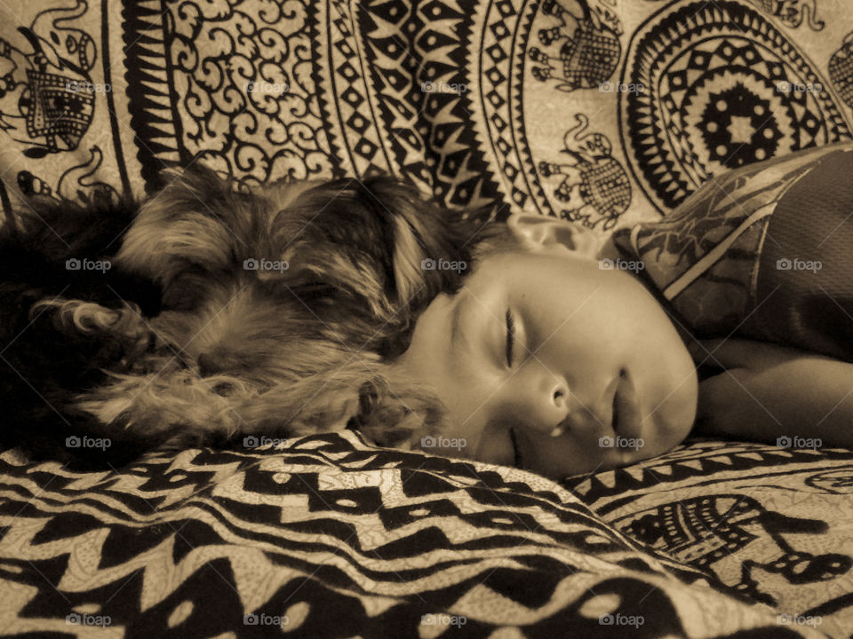 Niño y perro durmiendo cabeza contra cabeza sepia