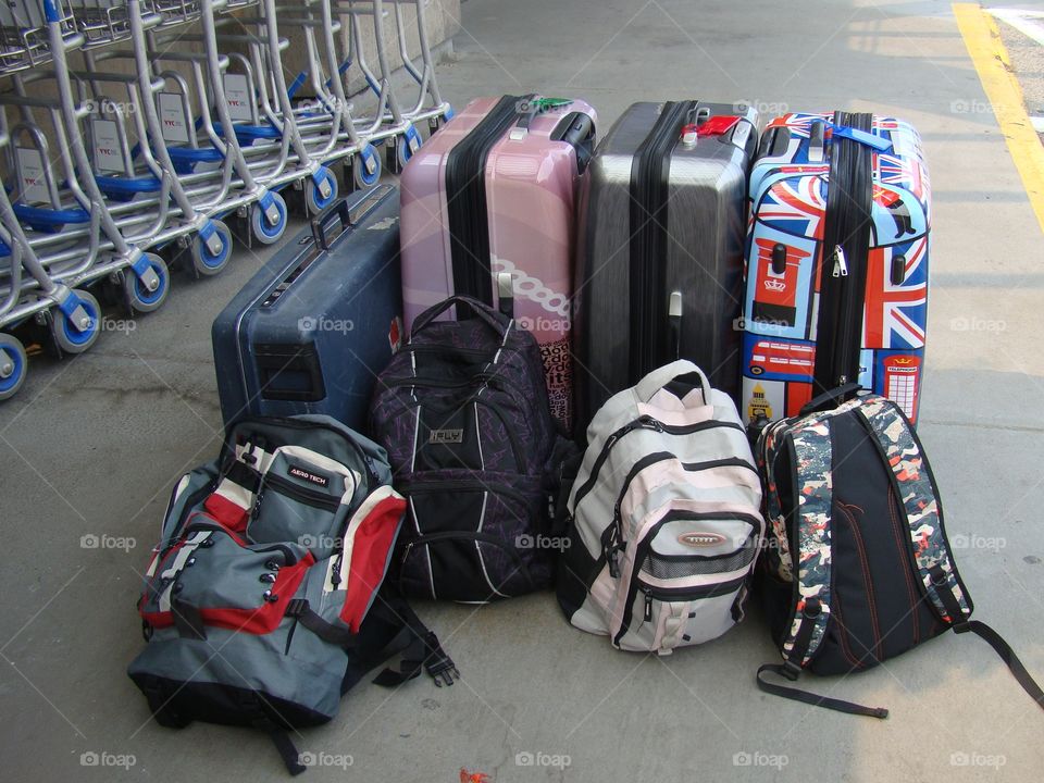 Colorful luggage by luggage carts, waiting for travel at the airport.
