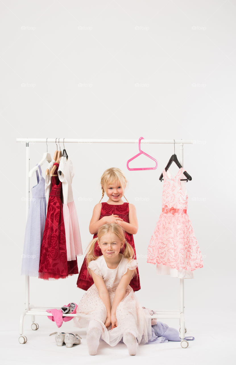 Two cute sisters is posing and playing with clothes and having fun.