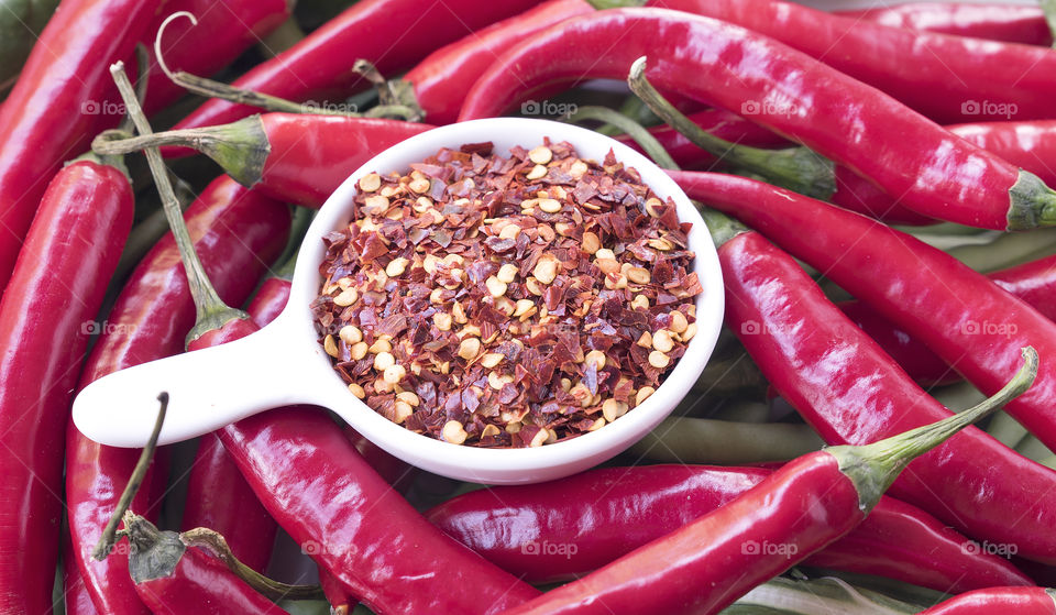 Dried red chilli in a white bowl with  raw red chillies .