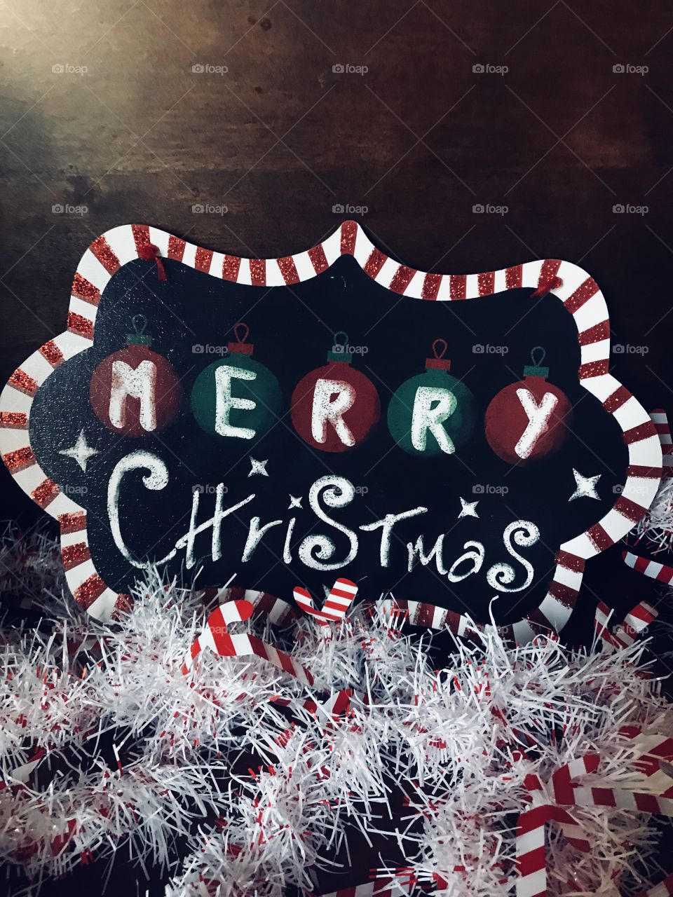 A colorful red, white, black and green Merry Christmas sign with beautiful white garland with candy canes on display 