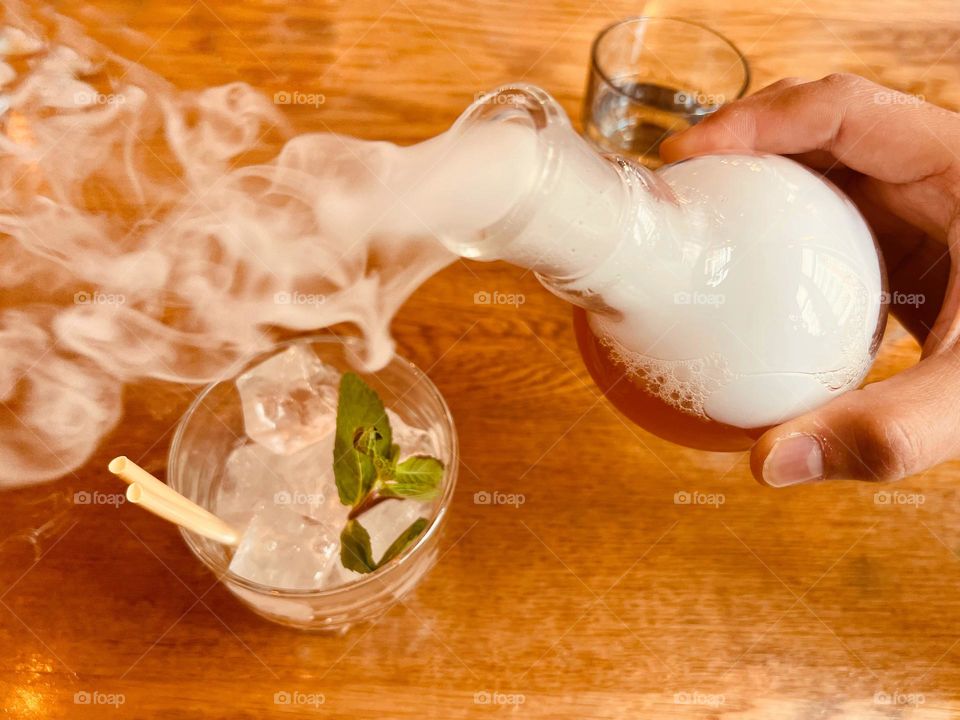 Pouring a fancy cocktail with dry ice into the glass