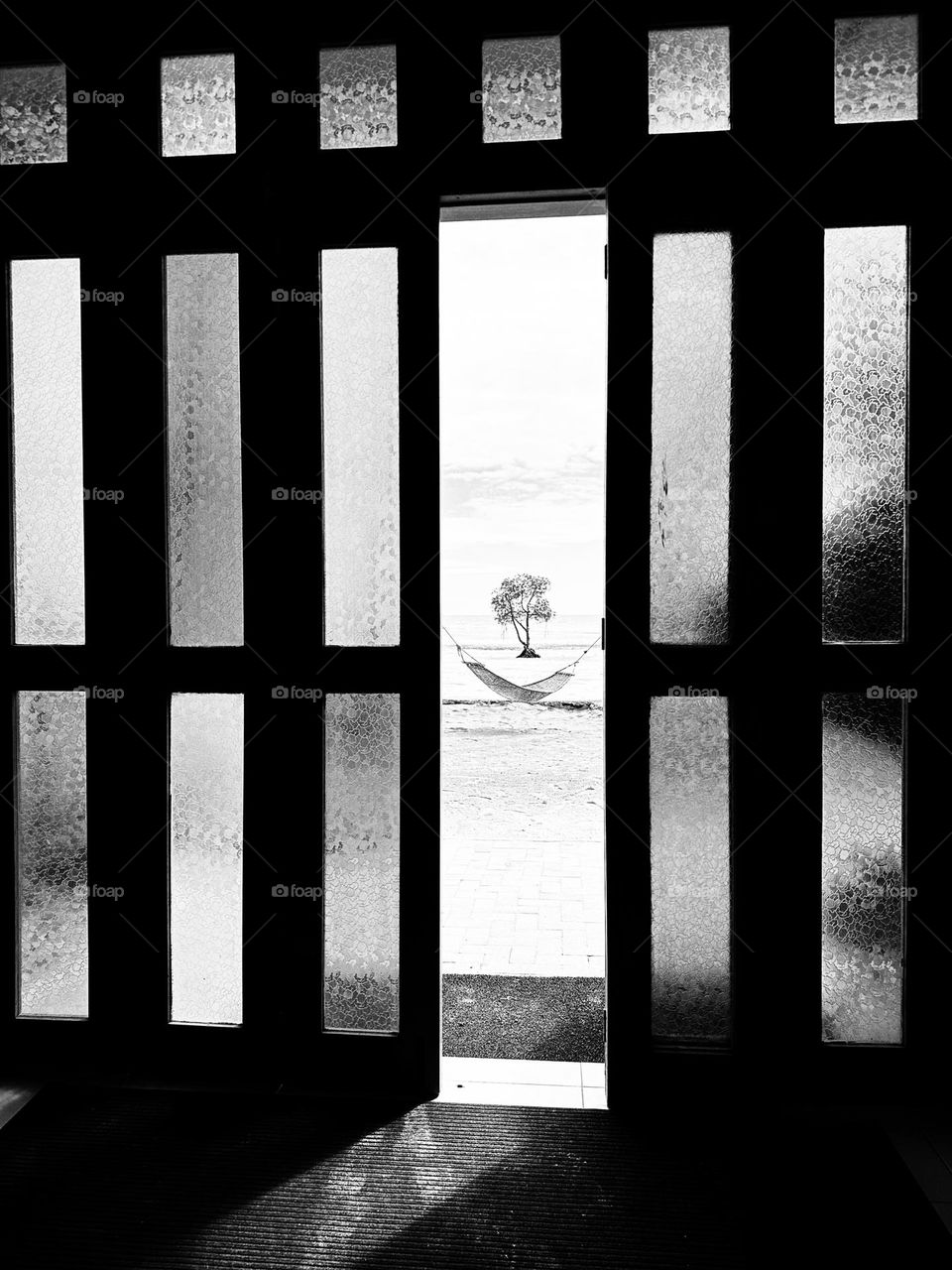 Beach front view from inside the hotel with natural framed with the doors in black and white. 