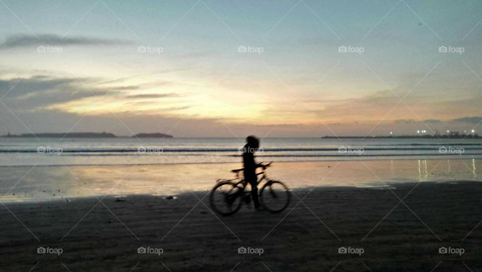 A boy riding a bicycle near the beach