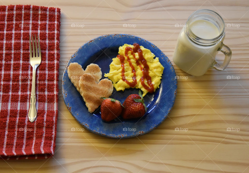Scrambled eggs with toast and fruit with a glass of milk