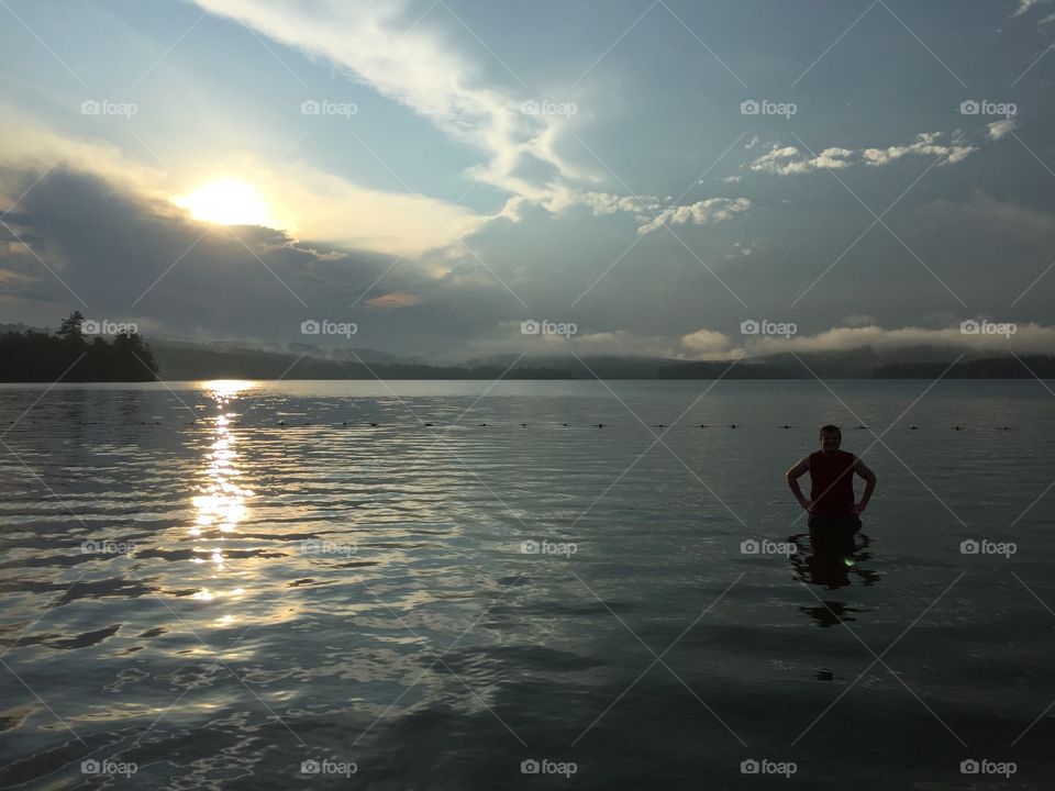 A sunset swim. Man swimming in Lake Waukewan, Meredith New Hampshire, at sunset.