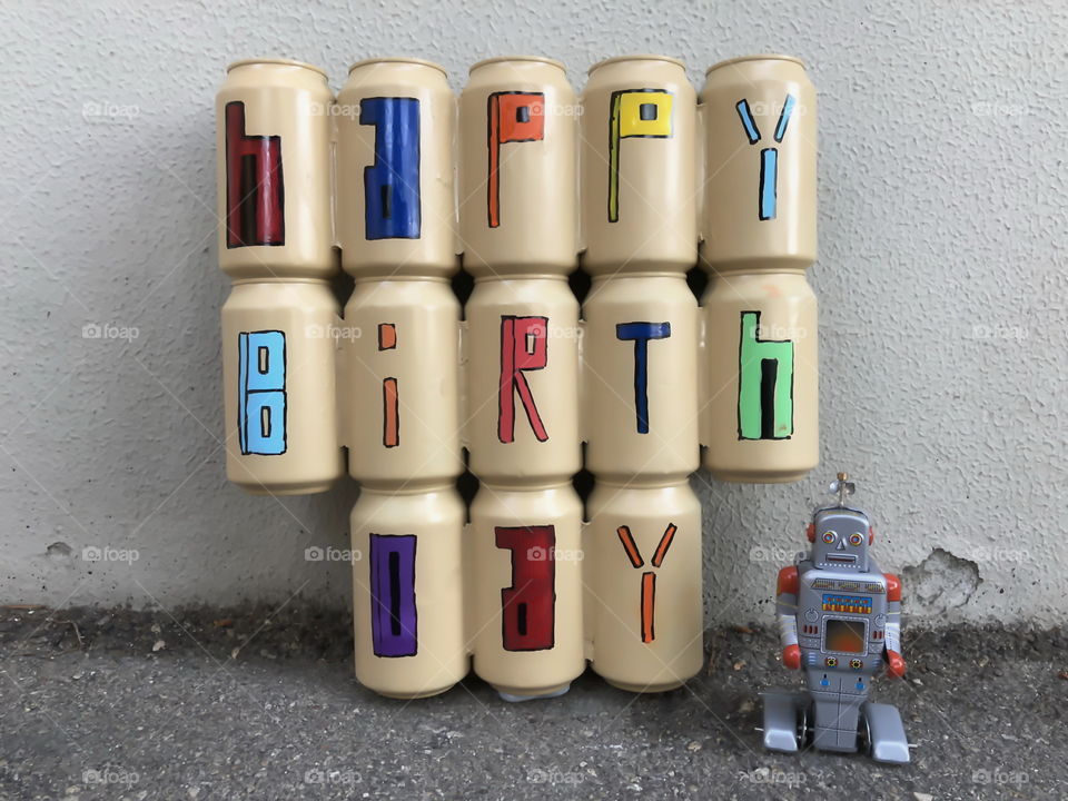 Happy Birthday text with colored beer cans and a tin toy robot