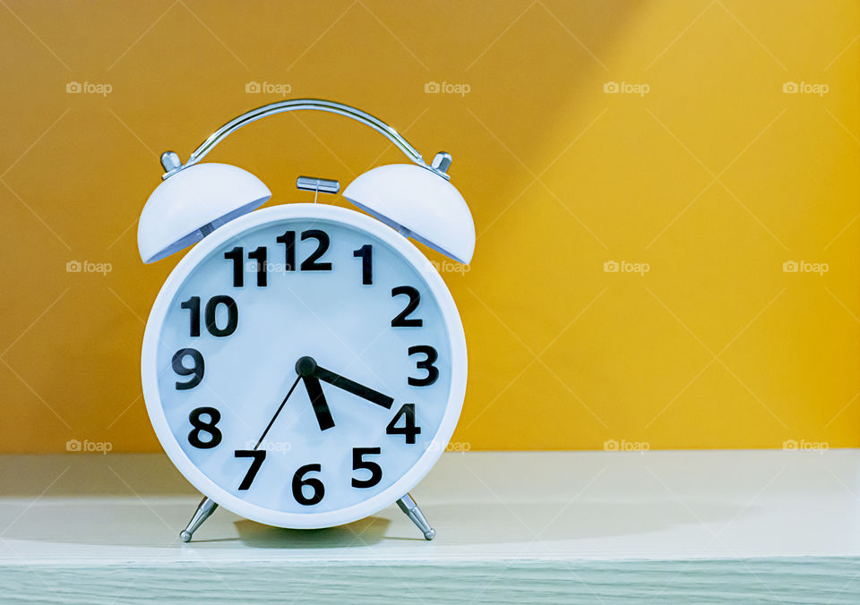 Alarm clock with a white and black dial on a orange background.