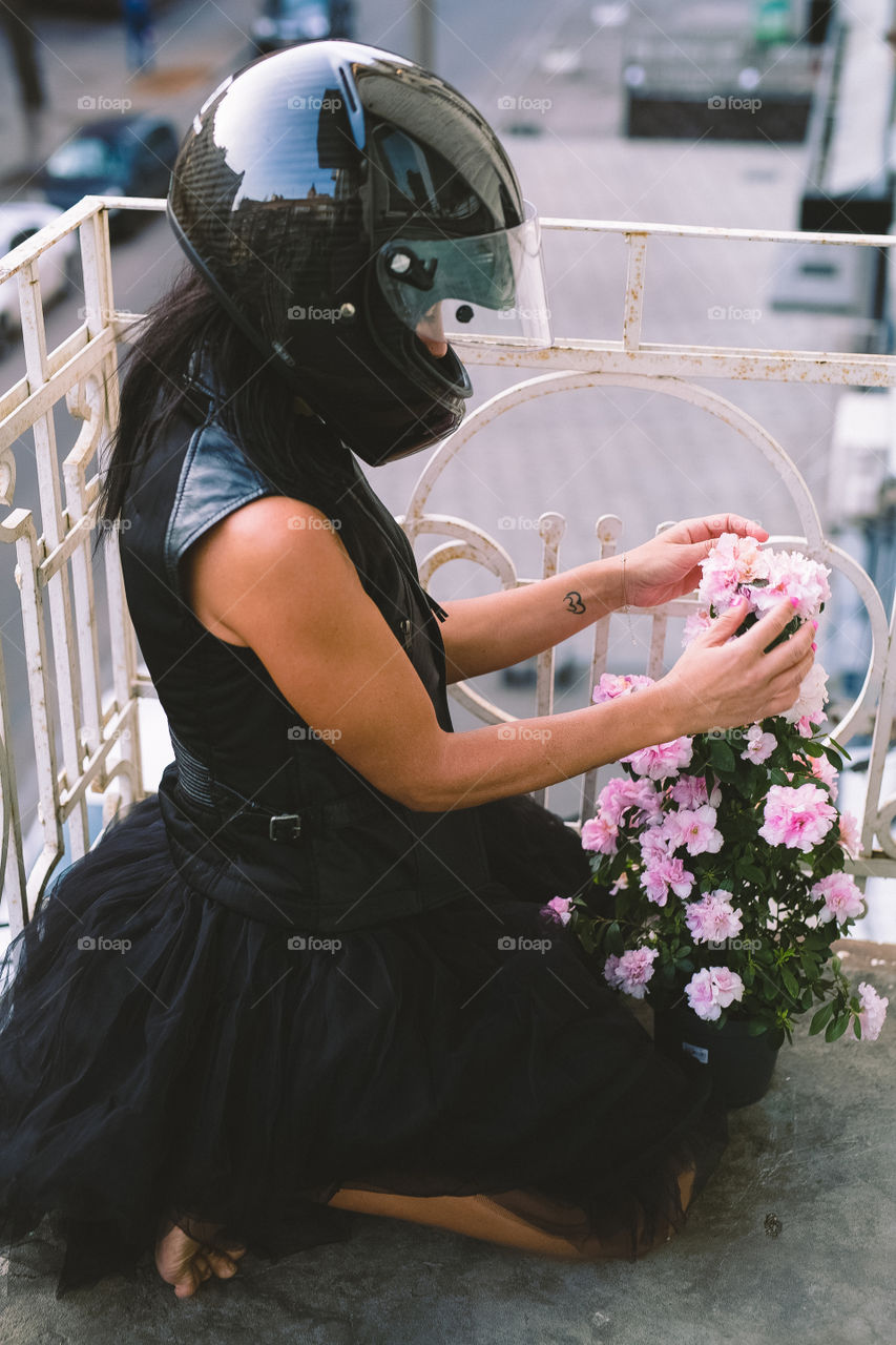 girl in black clothes, on her balcony taking care of flowers, spring mood, morning, home.  Flower in a flowerpot