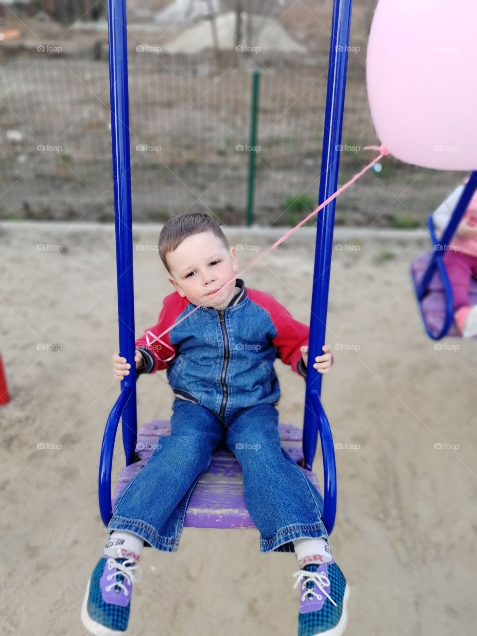 The boy sitting and hold the balloon