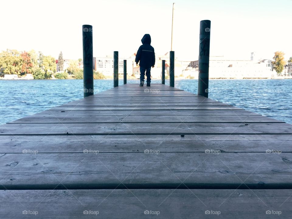 Young boy standing on a jetty. Young boy standing on a jetty in autumn clothes