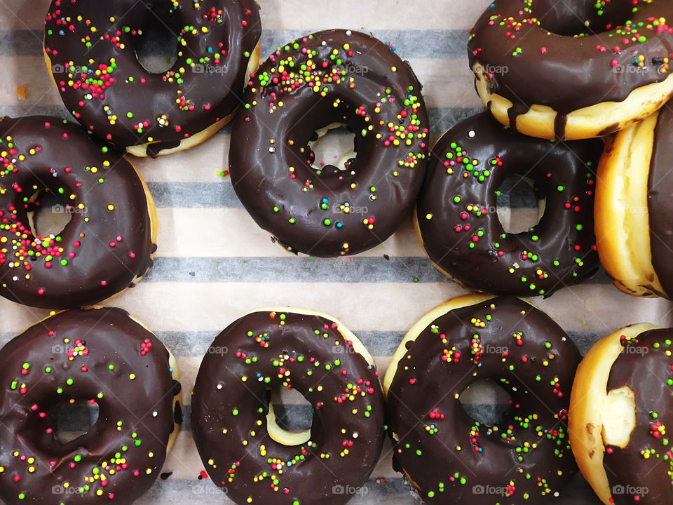 Fresh baked chocolate donuts with colorful sprinkles 