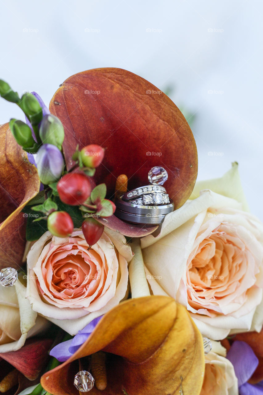 A bride and groom's wedding rings set inside a colourful wedding bouquet