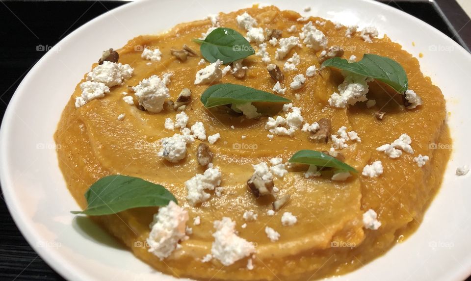 Butternut soup with basil leaves, nuts and feta cheese 